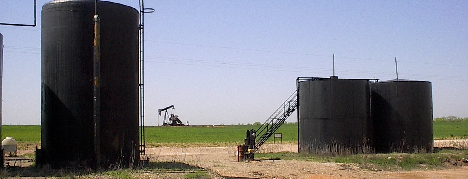 Oil and gas tank battery with pumpjack at sunrise
